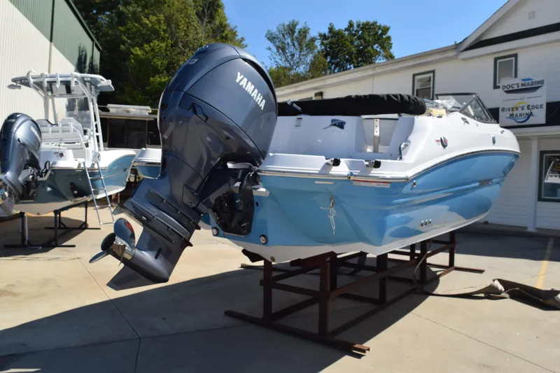 Slide: The Image of 2025 Stingray 211DC boat with Yamaha outboard motor on display at a marina. - 5