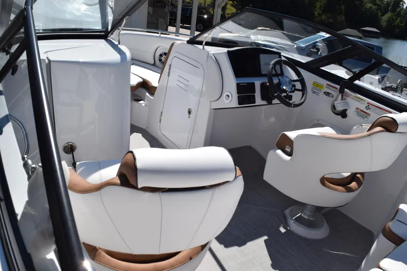Slide: The Image of 2025 Stingray 211DC boat interior with white and brown seating, modern dashboard, and steering wheel. - 9