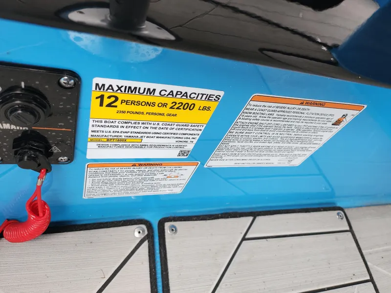 Slide: The Image of Yamaha Boats 2022 255XD capacity label, blue interior, 12-person limit, safety instructions visible. - 12