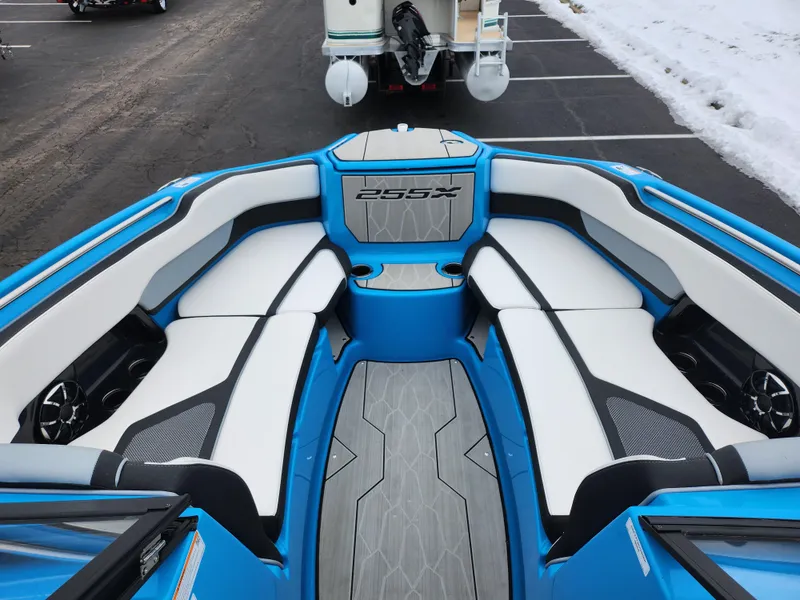 Slide: The Image of 2022 Yamaha Boats 255XD interior with blue and white seating, parked on a snowy day. - 15