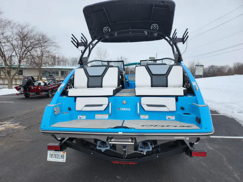 Slide: The Image of 2022 Yamaha Boats 255XD, blue exterior, parked on snowy pavement, rear view. - 2