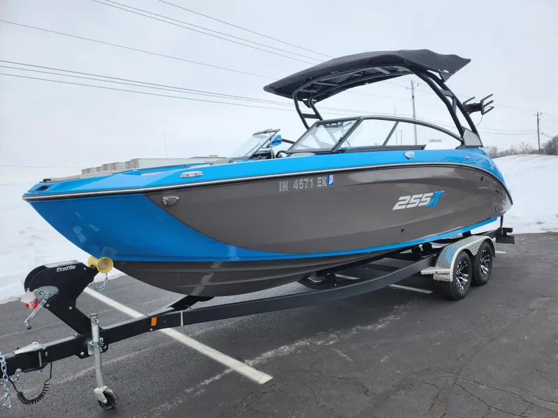 Slide: The Image of 2022 Yamaha Boats 255XD in blue and gray on a trailer, parked outdoors. - 5