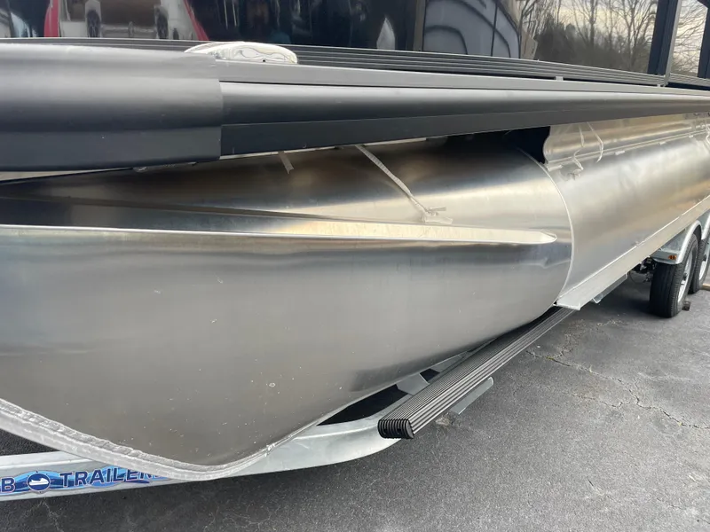 Slide: The Image of 2025 Harris Cruiser 210 pontoon boat on trailer, side view showing aluminum hull. - 1