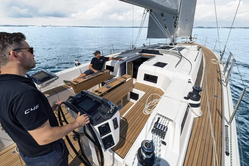 Slide: The Image of 2025 Bavaria C46 yacht sailing on calm waters, featuring modern deck design and advanced navigation controls. - 2