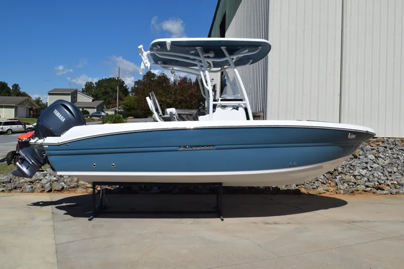 The Image of 2025 Stingray 216CC boat with Yamaha outboard, blue and white design, parked outdoors. - 1