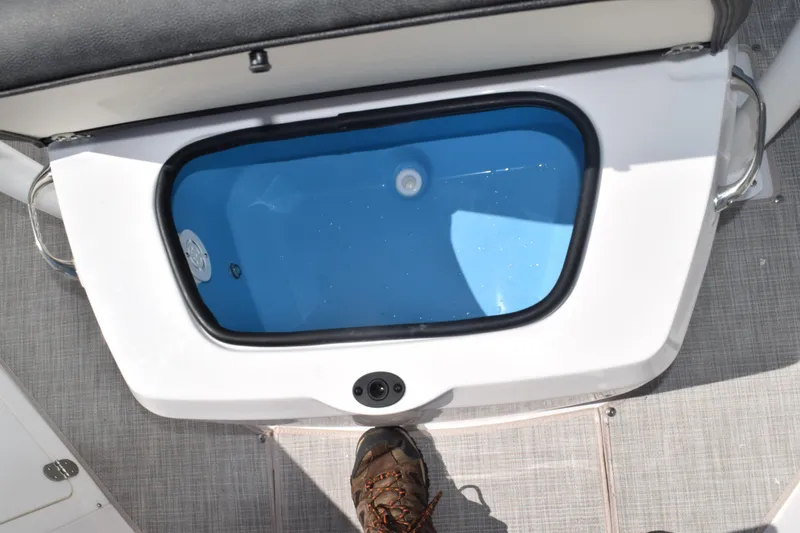 Slide: The Image of Livewell compartment on 2025 Stingray 216CC boat, featuring blue interior and foot pedal. - 23
