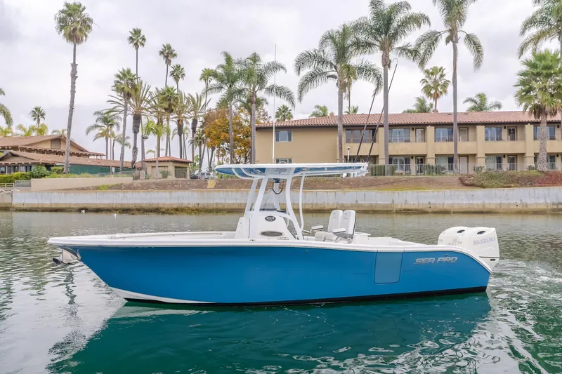 Slide: The Image of 2020 Seapro 25 DLX boat on water, with palm trees and buildings in the background. - 1