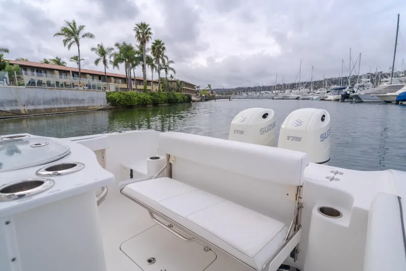 Slide: The Image of 2020 Seapro 25 DLX boat with dual engines docked in a marina, surrounded by palm trees. - 10