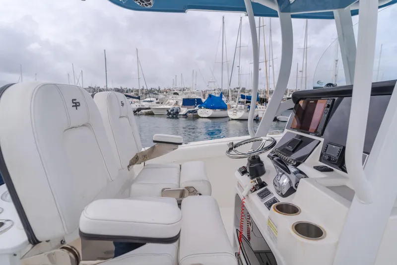 Slide: The Image of 2020 Seapro 25 DLX boat interior with white seating and modern dashboard at a marina. - 13