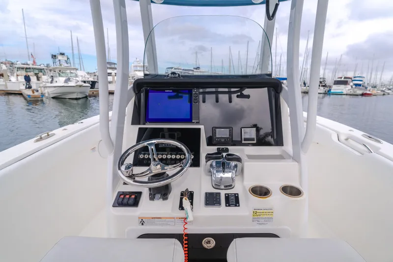 Slide: The Image of 2020 Seapro 25 DLX boat dashboard with steering wheel and navigation controls at marina. - 14