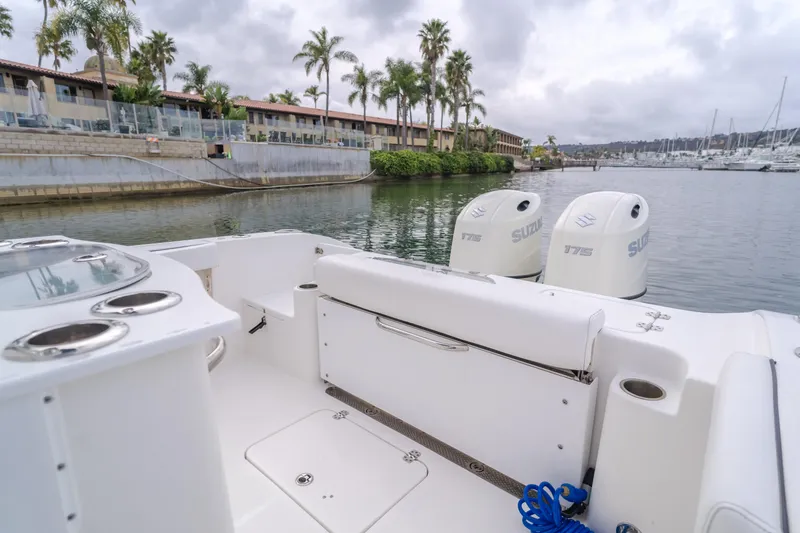 Slide: The Image of 2020 Seapro 25 DLX boat with dual Suzuki engines docked near palm trees and waterfront buildings. - 9
