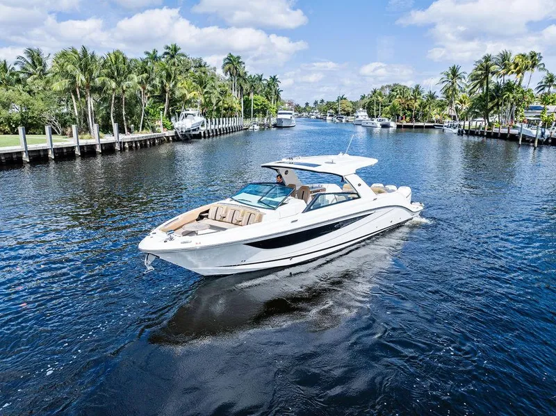 The Image of 2019 Sea Ray SLX 400 OB cruising on a scenic, palm-lined waterway. - 1