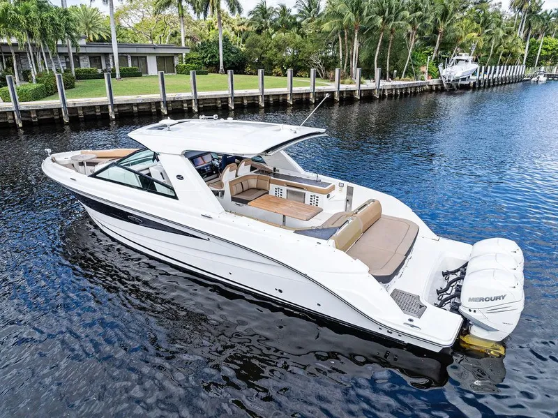 Slide: The Image of 2019 Sea Ray SLX 400 OB boat on a calm river, surrounded by lush greenery. - 16