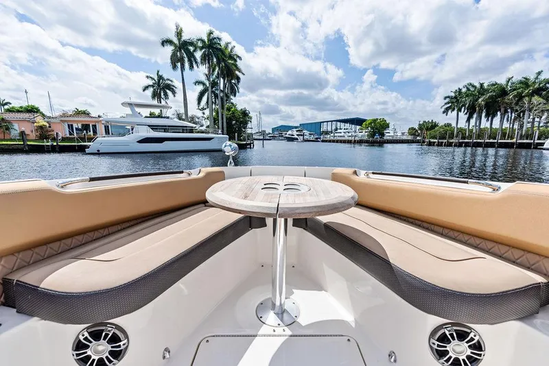 Slide: The Image of 2019 Sea Ray SLX 400 OB boat interior with seating and table, docked by palm trees. - 18