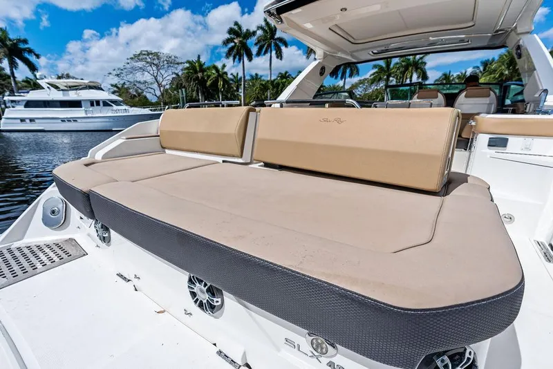Slide: The Image of 2019 Sea Ray SLX 400 OB luxury boat with spacious sunbed and scenic marina backdrop. - 24
