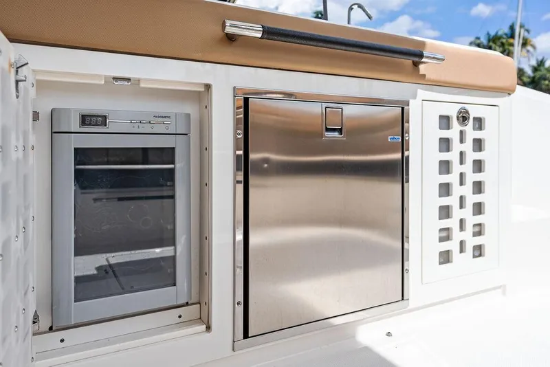 Slide: The Image of 2019 Sea Ray SLX 400 OB boat galley with fridge and stainless steel storage. - 28