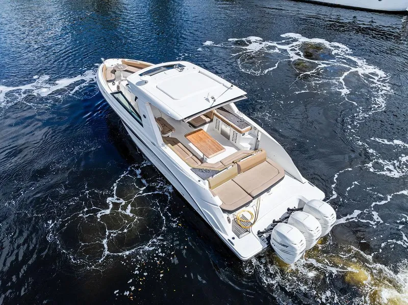 Slide: The Image of 2019 Sea Ray SLX 400 OB boat cruising on water, featuring spacious deck and triple outboard engines. - 4