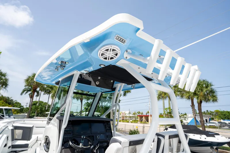 Slide: The Image of 2023 Blackfin 302CC boat with blue T-top and rod holders, palm trees in background. - 29
