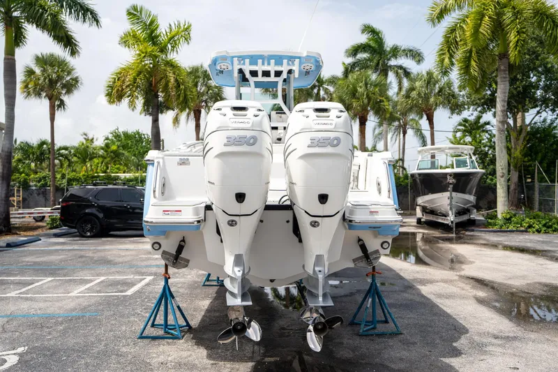 Slide: The Image of 2023 Blackfin 302CC boat with twin 350 engines on display, surrounded by palm trees. - 3