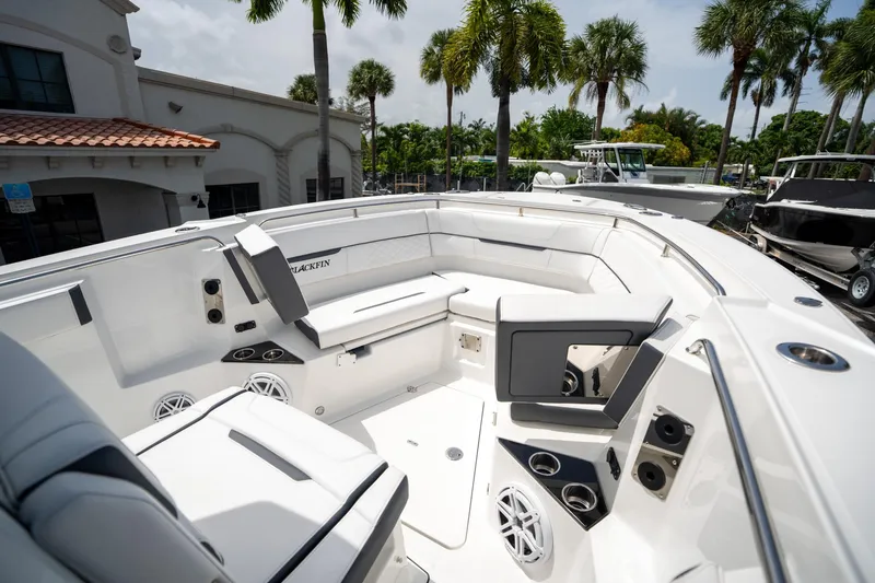 Slide: The Image of 2023 Blackfin 302CC boat interior with seating and cup holders, surrounded by palm trees. - 41