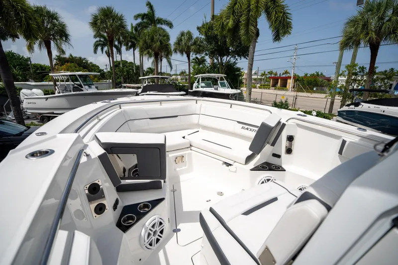 Slide: The Image of 2023 Blackfin 302CC boat interior with seating, cup holders, and speakers, surrounded by palm trees. - 42