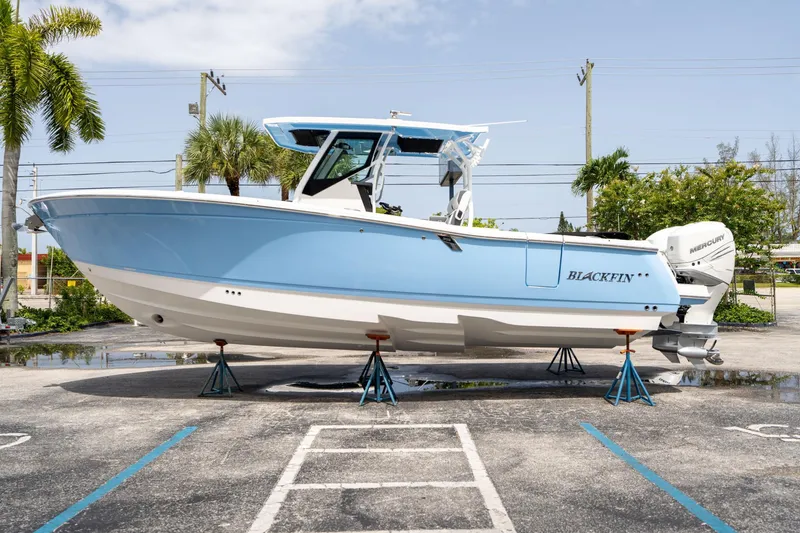 Slide: The Image of 2023 Blackfin 302CC boat on stands, displayed outdoors with palm trees. - 5