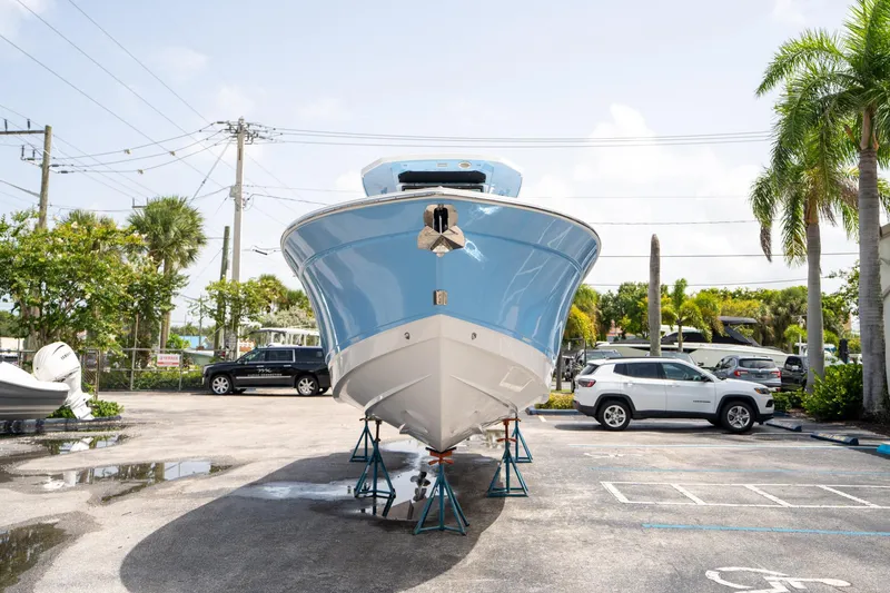Slide: The Image of 2023 Blackfin 302CC boat on stands in a parking lot, surrounded by cars and palm trees. - 7