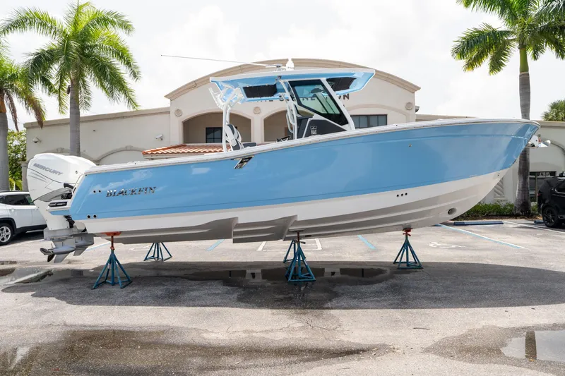 Slide: The Image of 2023 Blackfin 302CC boat displayed on stands in a parking lot. - 1