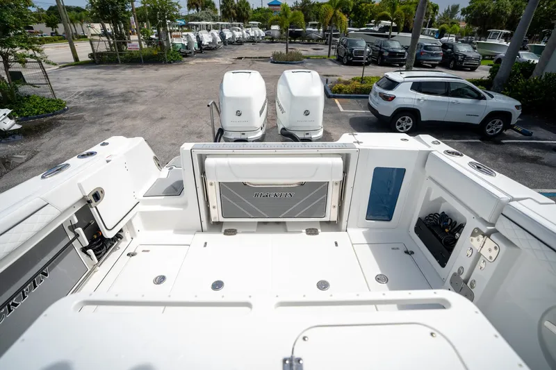 Slide: The Image of 2023 Blackfin 302CC boat deck with dual outboard engines in a parking lot. - 12