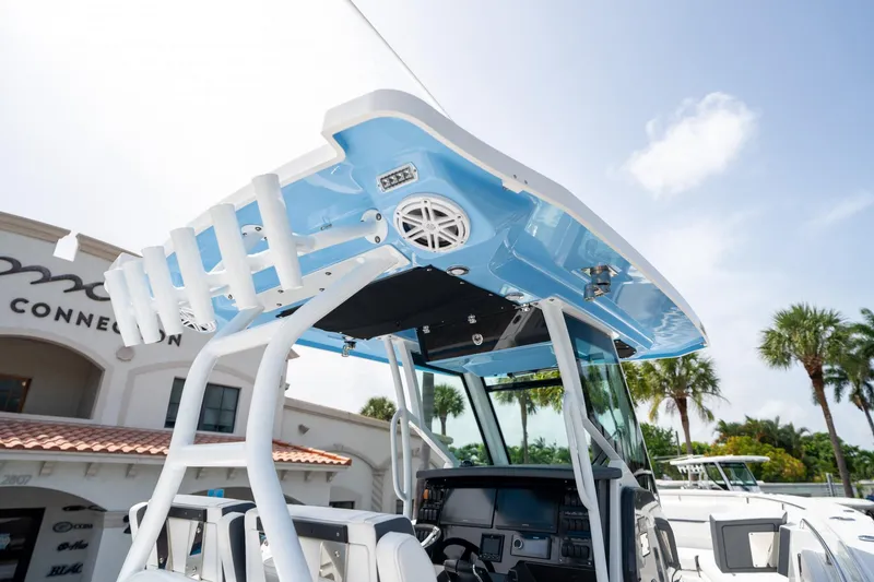 Slide: The Image of 2023 Blackfin 302CC boat with blue T-top and rod holders, displayed outdoors. - 28