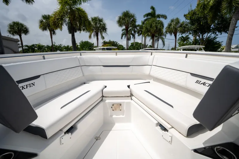 Slide: The Image of 2023 Blackfin 302CC boat interior with white seating, surrounded by palm trees. - 44