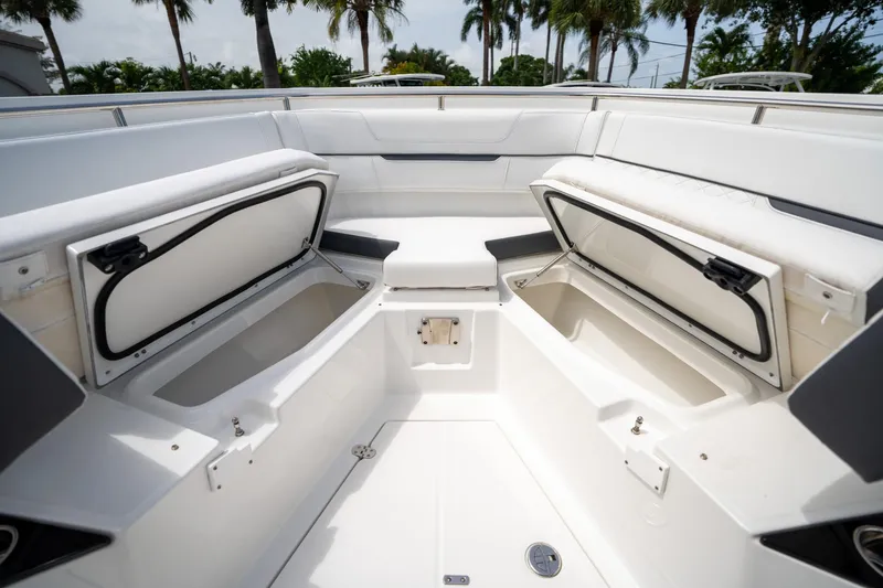 Slide: The Image of 2023 Blackfin 302CC boat interior with open storage compartments, white seating, and palm trees in background. - 46