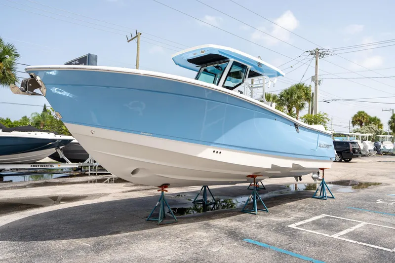 Slide: The Image of 2023 Blackfin 302CC boat on stands, light blue hull, outdoor display. - 6