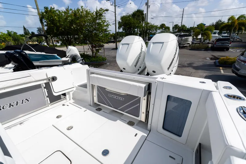 Slide: The Image of 2023 Blackfin 302CC boat with dual Mercury engines, docked in a marina. - 17