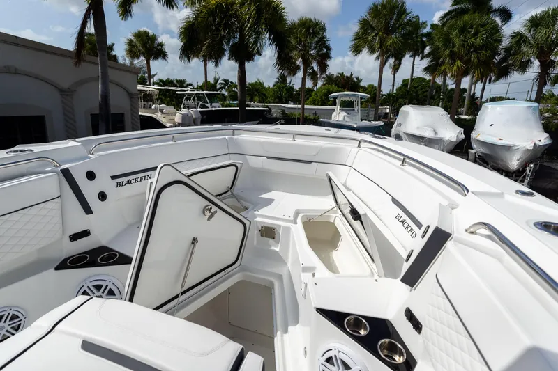 Slide: The Image of 2023 Blackfin 302CC boat interior with open storage compartments, surrounded by palm trees. - 46