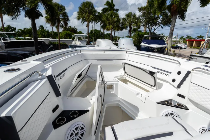 Slide: The Image of 2023 Blackfin 302CC boat interior with open storage compartments, surrounded by palm trees. - 48