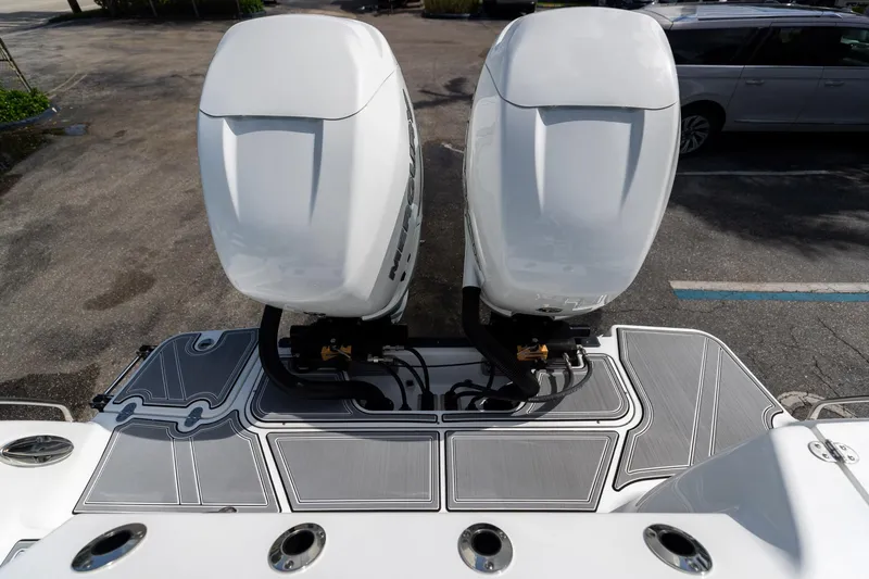 Slide: The Image of 2023 Blackfin 302CC boat with dual outboard engines, parked on a textured surface. - 11