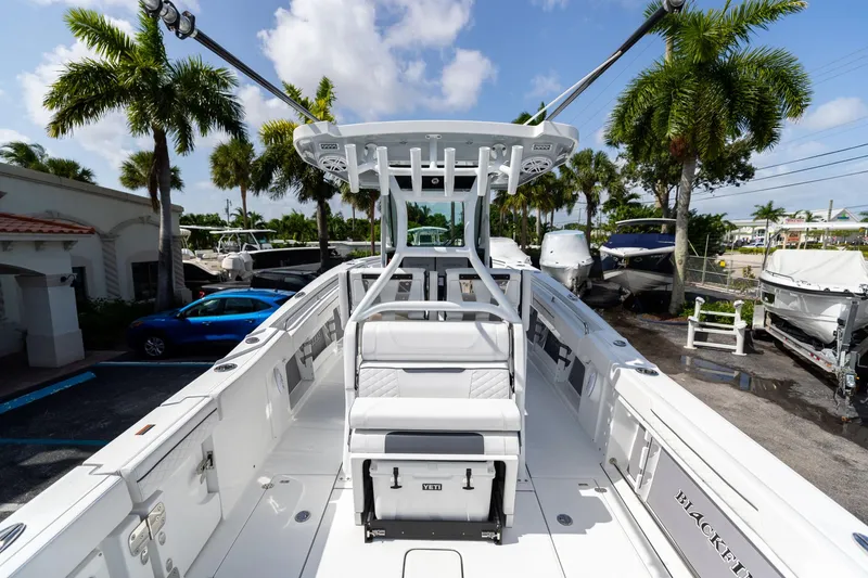 Slide: The Image of 2023 Blackfin 302CC boat with sleek design, docked under palm trees. - 12