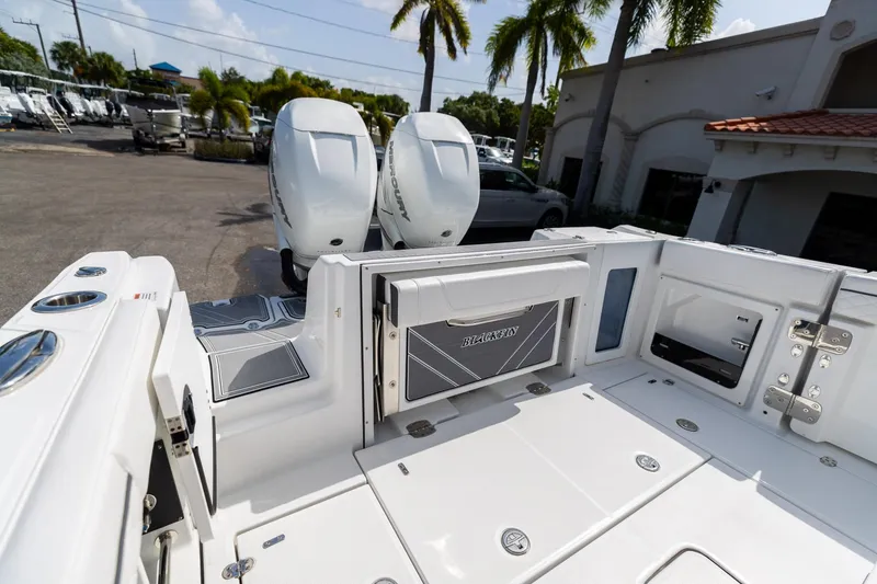 Slide: The Image of 2023 Blackfin 302CC boat with dual outboard engines, docked under palm trees. - 13