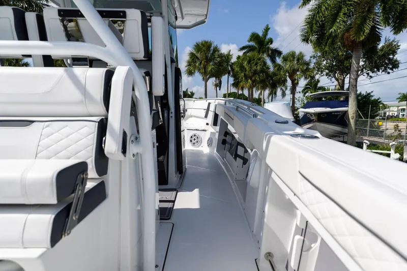 Slide: The Image of 2023 Blackfin 302CC boat interior with white seating and palm trees in the background. - 19