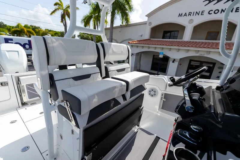 Slide: The Image of 2023 Blackfin 302CC boat interior with modern seating and steering wheel, parked near a marine store. - 37