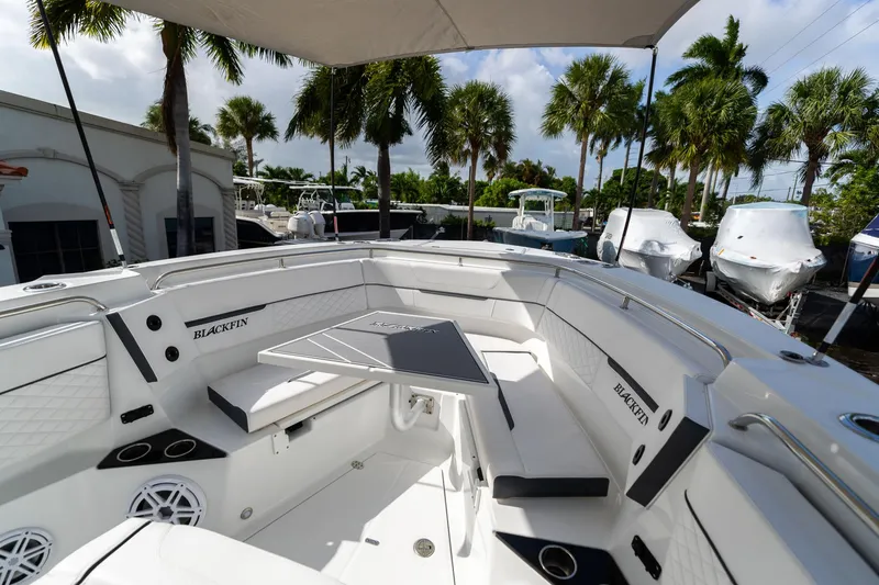 Slide: The Image of 2023 Blackfin 302CC boat interior with seating and table, surrounded by palm trees. - 45