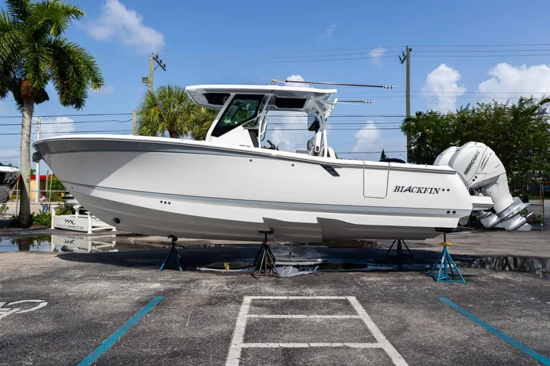 Slide: The Image of 2023 Blackfin 302CC boat on stands, displayed outdoors under a clear blue sky. - 6