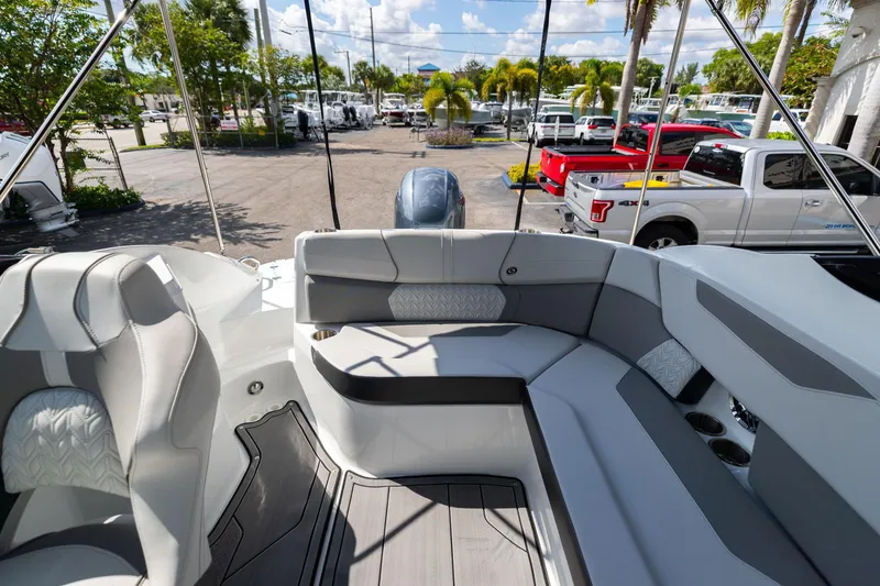 Slide: The Image of 2023 Hurricane SunDeck 2200 OB boat interior with gray seating and parked vehicles in the background. - 13