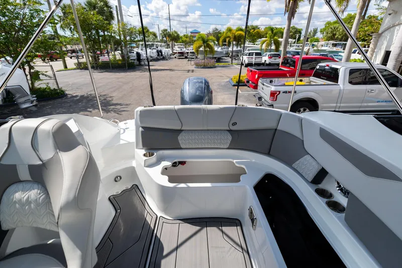 Slide: The Image of 2023 Hurricane SunDeck 2200 OB boat interior with seating and cup holders, parked outdoors. - 14