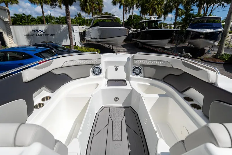 Slide: The Image of 2023 Hurricane SunDeck 2200 OB boat interior with seating and cup holders, parked outdoors. - 32