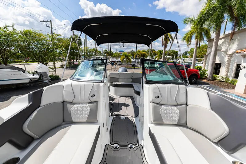 Slide: The Image of 2023 Hurricane SunDeck 2200 OB boat interior with seating, canopy, and windshield under a sunny sky. - 37