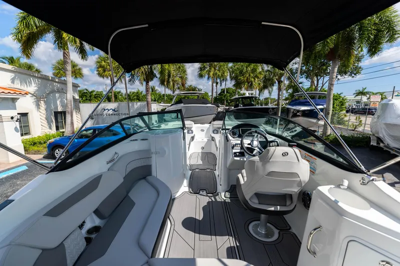 Slide: The Image of 2023 Hurricane SunDeck 2200 OB boat interior with seating and steering wheel, under a canopy. - 9