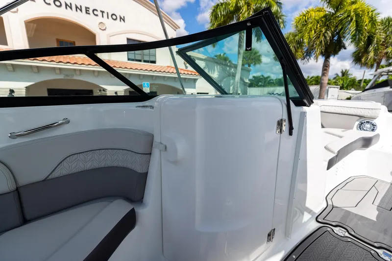 Slide: The Image of 2023 Hurricane SunDeck 2200 OB interior with seating, windshield, and palm trees in the background. - 25