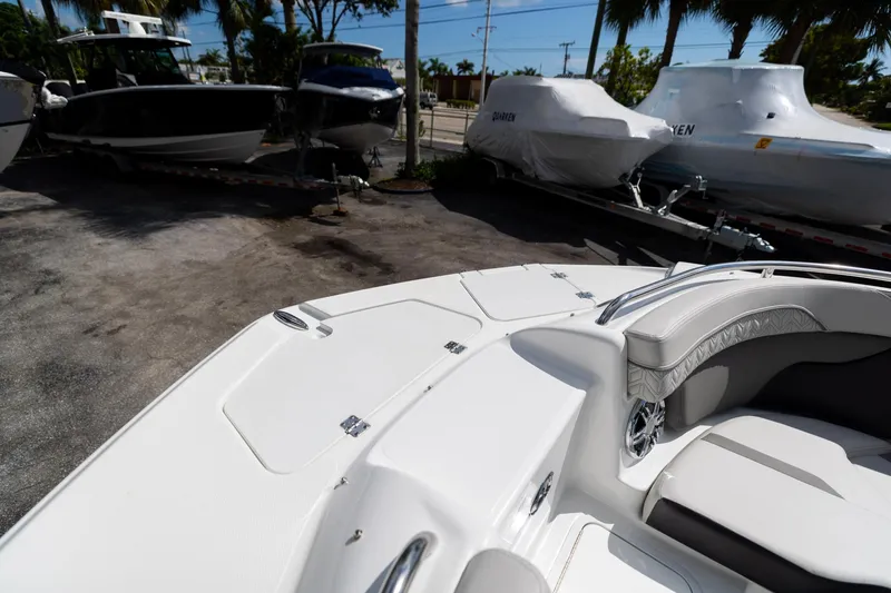 Slide: The Image of 2023 Hurricane SunDeck 2200 OB boat, white interior, parked with other boats under cover. - 35